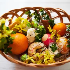 Inspiracja, jak przystroić koszyczek wielkanocny: pisanki, pomarańcze, babeczka, baranek i bukszpan tworzą wiosenną kompozycję.