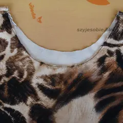 Wykończony dekolt sukienki w panterkę z lamówką.