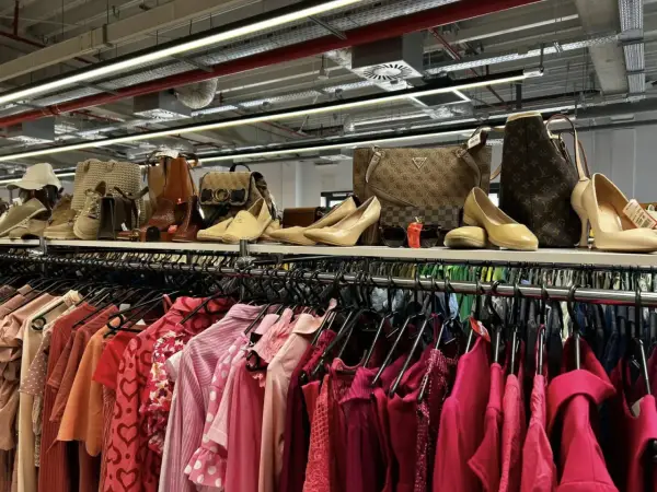 Półka pełna torebek i butów, a pod nią rząd różowych ubrań. Idealne miejsce na przerabianie ubrań i tworzenie nowych stylizacji.